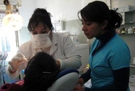 Volunteer Medicine & Healthcare A destist examines a patient's teeth and gums while an assistant observes
